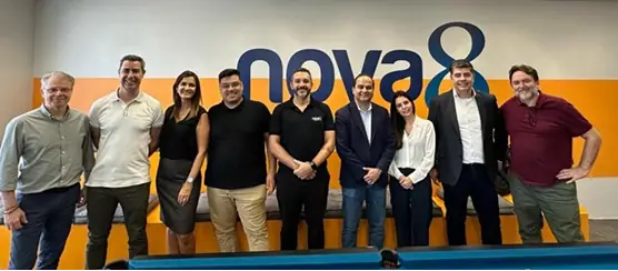 Equipe da Nova8 em frente ao logotipo da empresa