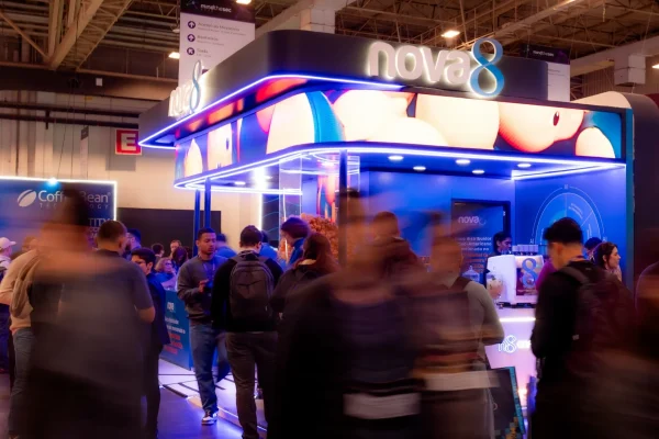 Estande da Nova8 iluminado em azul no evento Mind The Sec 2026, com visitantes circulando em frente